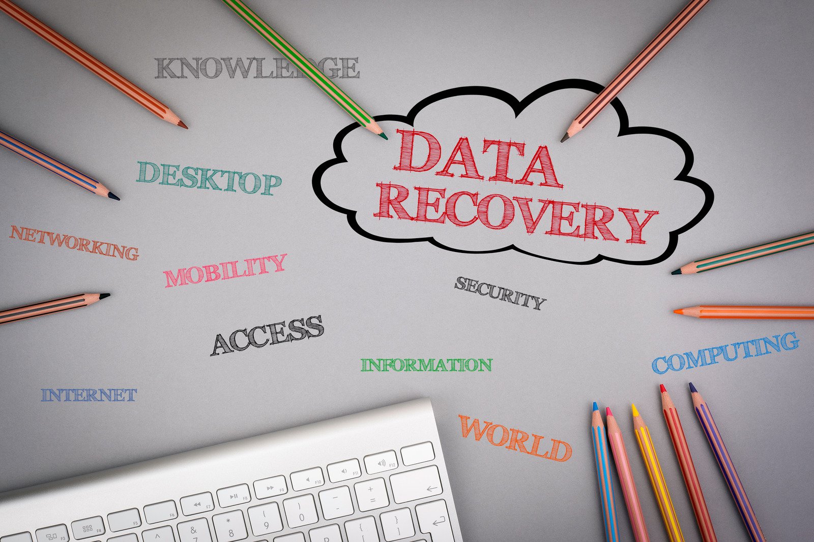 Data Recovery word cloud. Colored pencils and a computer keyboard on the table.